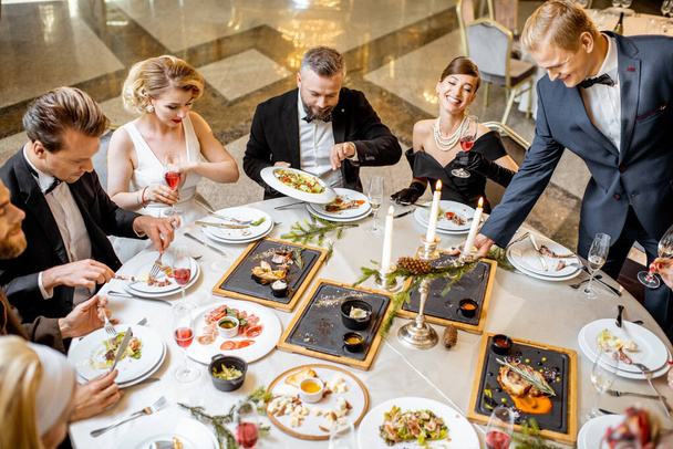 Elegantemente vestidos personas teniendo una cena festiva en el interior
 - Foto, Imagen