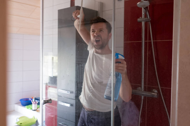 Caucasian man cleaning his shower stall at home - Foto, afbeelding