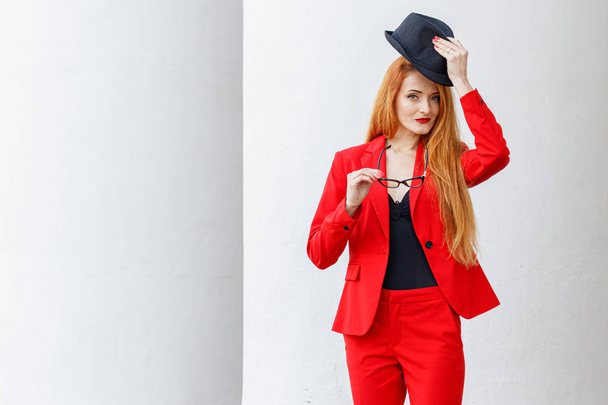 beautiful girl with red hair dressed in a red business suit. Bus - Photo, Image