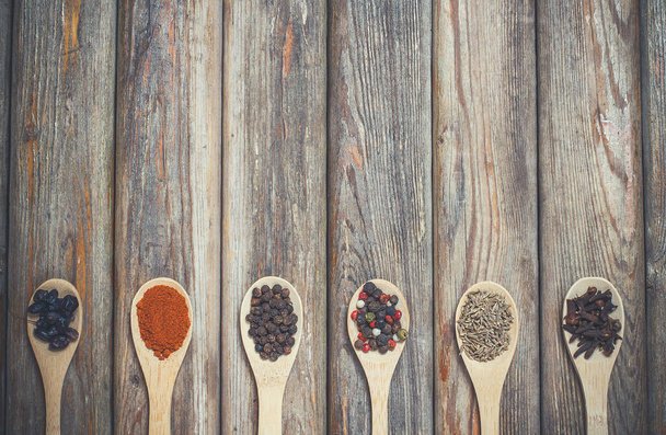 Different spices and salt lie in wooden spoons on a wooden table - Photo, image