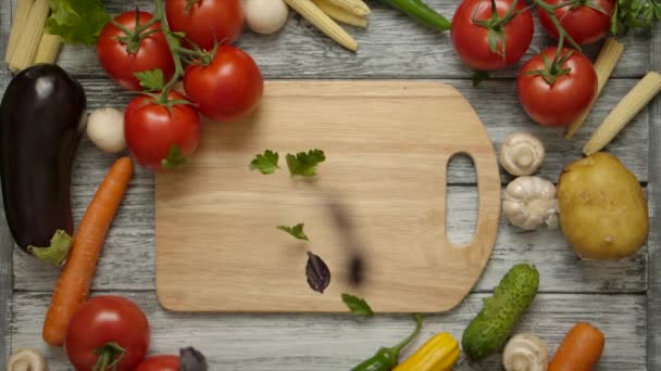 Parsley piecesfalling on a cutting board with vegetables around - Footage, Video