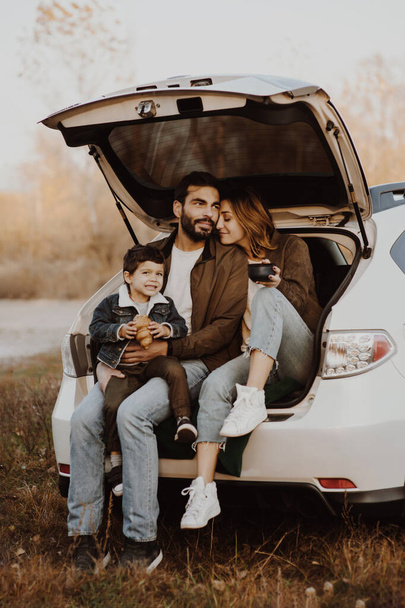 Happy family sitting in a car trunk. - Foto, Imagem