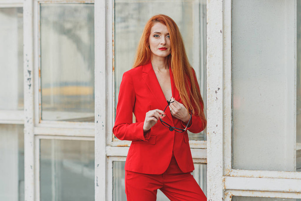 hermosa chica con el pelo rojo vestido con un traje de negocios rojo. Autobús
 - Foto, imagen