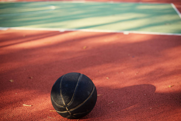 Red and green street basketball court with black ball. - Fotografie, Obrázek