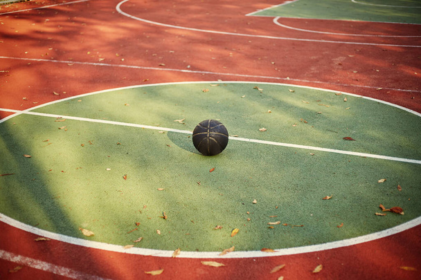 Red and green street basketball court with black ball. - Fotoğraf, Görsel