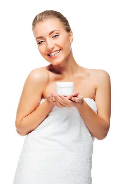 Beautiful girl holding and showing cream for care of skin body. Young woman in towel on white background. Cosmetics for hydrating and rejuvenating. - Foto, Imagem