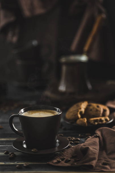 Een kopje koffie met schuim op een donkere houten achtergrond met haver - Foto, afbeelding