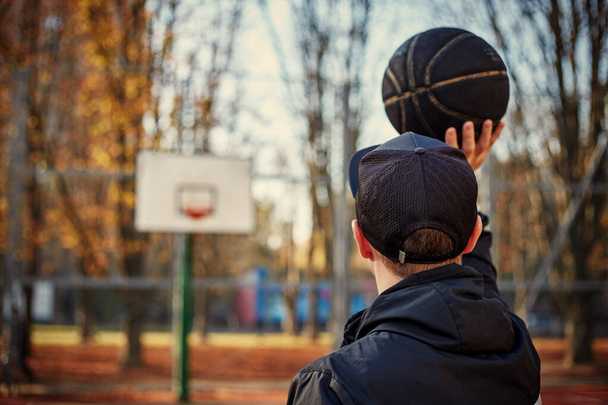Rear view of a basketball player, shooting at basket outdoor. - Photo, Image