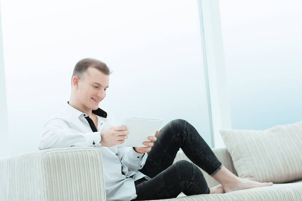 smiling man with digital tablet sitting on sofa in his living room - Φωτογραφία, εικόνα