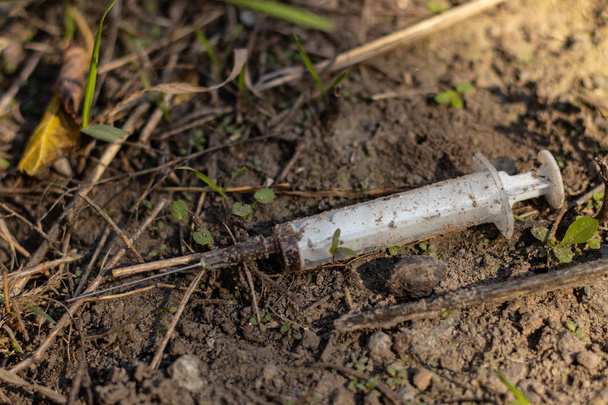 used syringe with blood lies on the ground - Фото, зображення