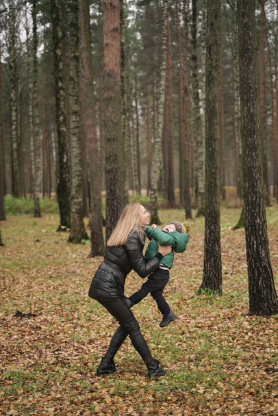 hermosa madre caucásica y el niño pequeño se divierten en el otoño Parque, caminando. madre sostiene al niño en sus brazos
 - Foto, imagen