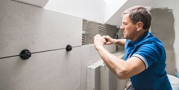 man installing tiles on wall. home indoors renovation - Fotó, kép