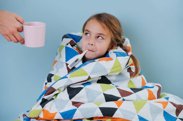 Sick little girl with common cold wrapped in blanket, measuring temperature. - Foto, immagini