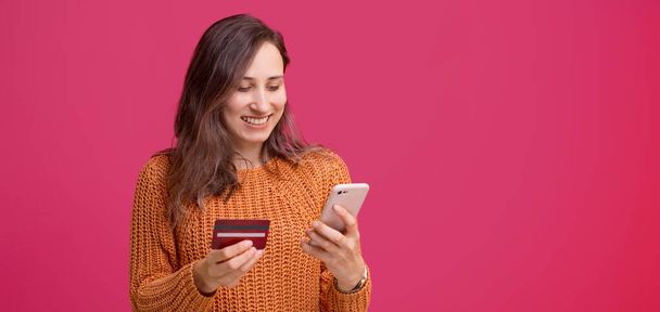 Cheerful young woman using his smartphone and holding credit card, mobile web banking - Foto, Imagen