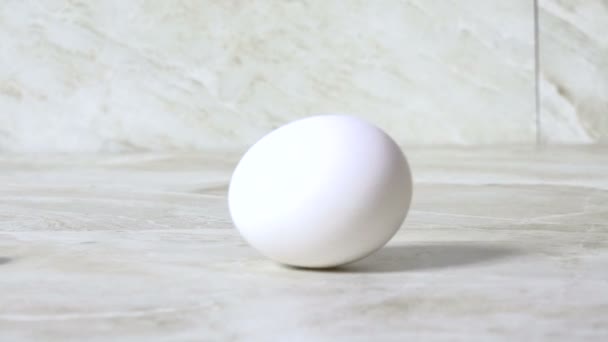 A raw egg spinning on a counter top - Video
