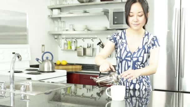 Asian girl is drinking coffee in the kitchen - Video, Çekim