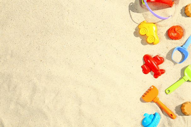 Flat lay composition with plastic beach toys on sand. Space for text - 写真・画像