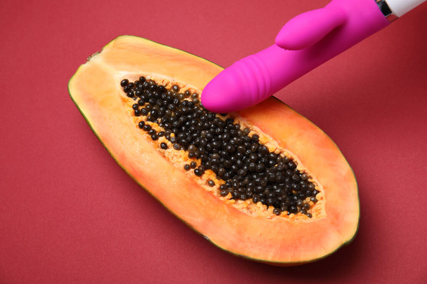 Half of papaya and purple vibrator on red background, above view. Sex concept - Photo, Image