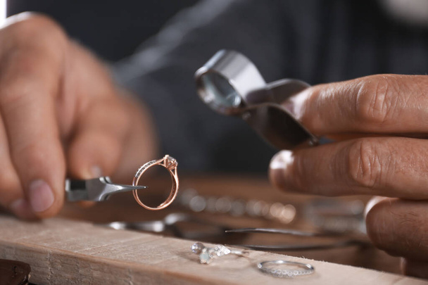 Male jeweler examining diamond ring in workshop, closeup view - Foto, Imagen