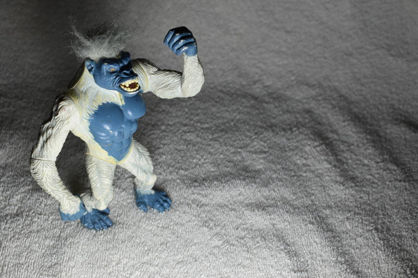 Modrá a bílá gorila hračka třese pěstí ve vzduchu na bílém plátně. - Fotografie, Obrázek