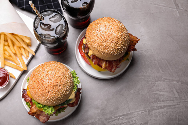 Composition with juicy bacon burgers on grey table, above view - Foto, imagen