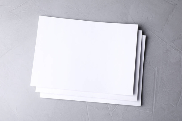 Blank paper sheets on light grey stone background, top view. Mock up for design - Fotoğraf, Görsel