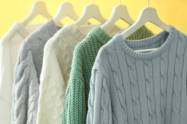 Collection of warm sweaters on yellow wall, closeup - Zdjęcie, obraz