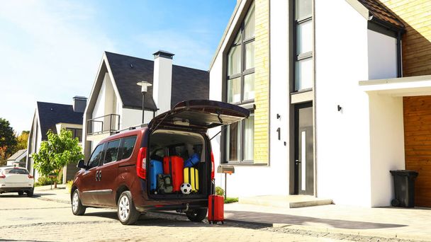 Car with suitcases in trunk near modern house outdoors. Moving day - Fotoğraf, Görsel