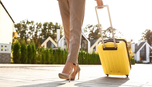 Woman with yellow suitcase outdoors. Moving day - Foto, Bild
