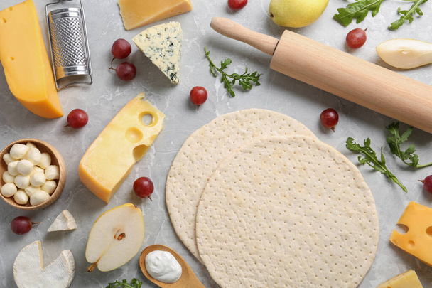 Flat lay composition with pizza crusts and fresh ingredients on marble table - Foto, imagen