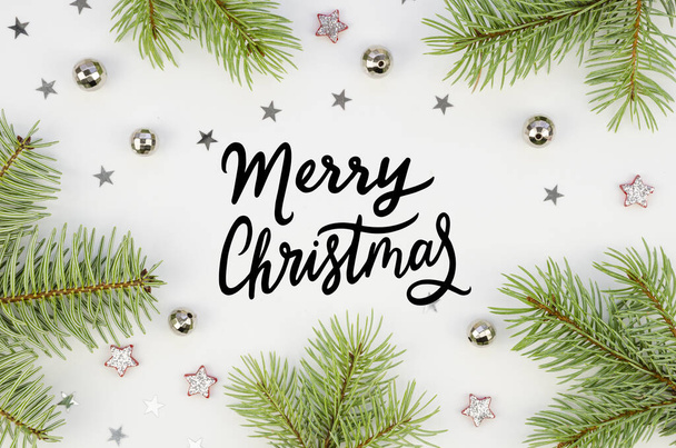 Flat lay border made of branches of a Christmas tree with Christmas decorations on a white background with lettering Merry Christmas text - Fotoğraf, Görsel