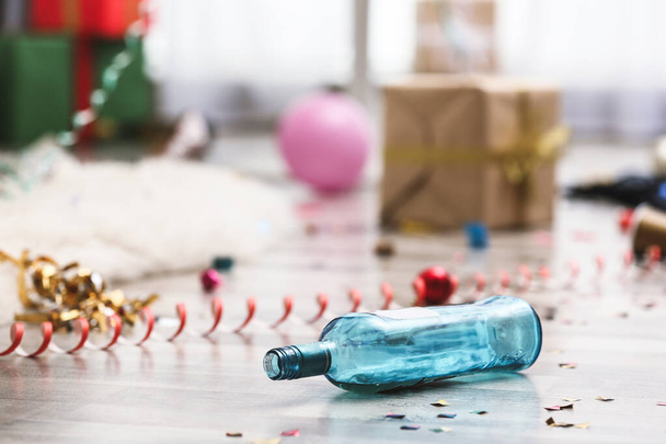 Empty bottle and confetti on messy floor. Chaos after party - Fotografie, Obrázek