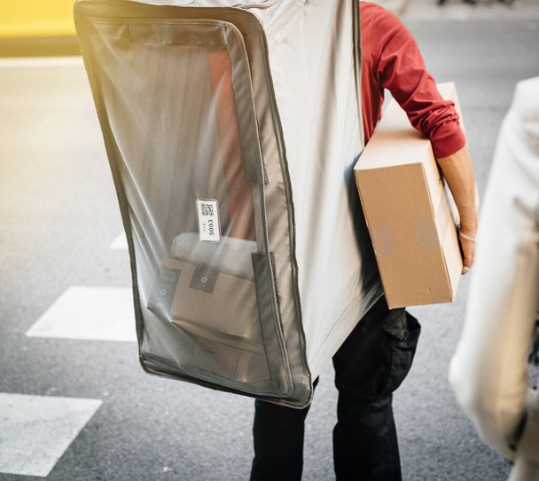 Karton kutu taşıyan ve ekstra büyük bavul taşıyan bir işçi. - Fotoğraf, Görsel
