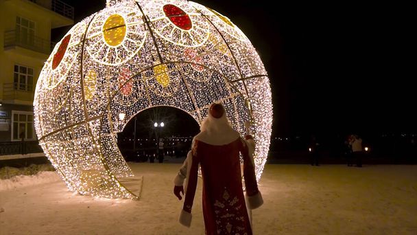 サンタのリアビュー街のクリスマスライトの装飾に夜、冬の休日のコンセプトに来るClous 。クリップ。ガーランドで覆われた驚くべき球状の燃焼. - 写真・画像