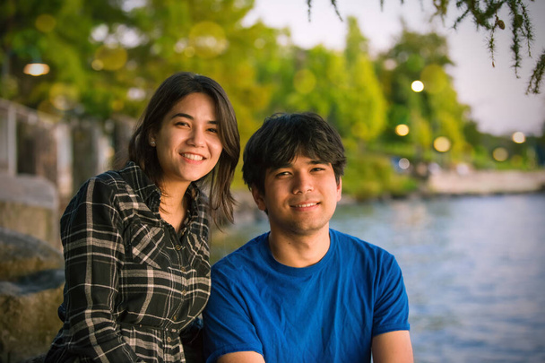 Young biracial Asian Caucasian young people by lake at sunset - 写真・画像