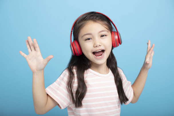 happy little girl with headphones listening and singing song - Photo, Image