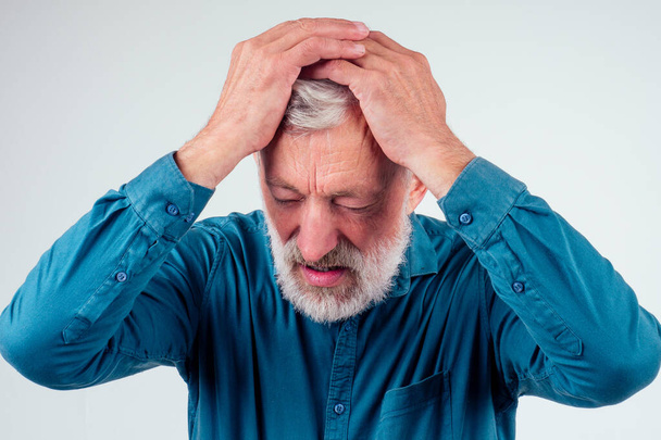 Elderly man with hand on his temple has a headache in studio white background - Photo, image