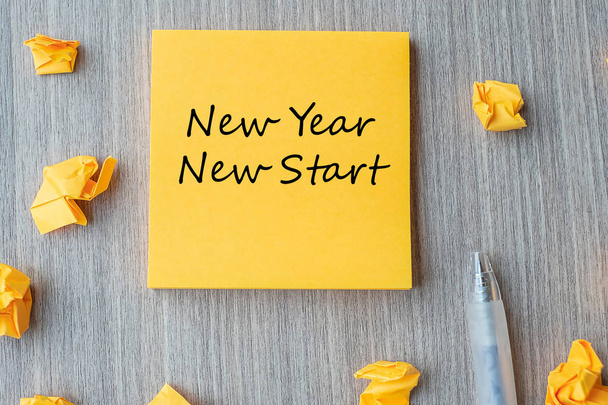 Nowy Rok Nowy Start słowa na żółtej nucie z piórem i rozdrobnione pap - Zdjęcie, obraz