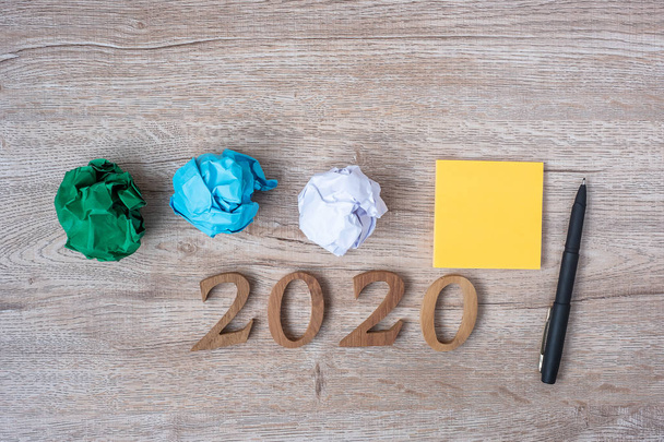 Feliz año nuevo 2020 con nota amarilla, papel desmenuzado y pluma en
  - Foto, Imagen