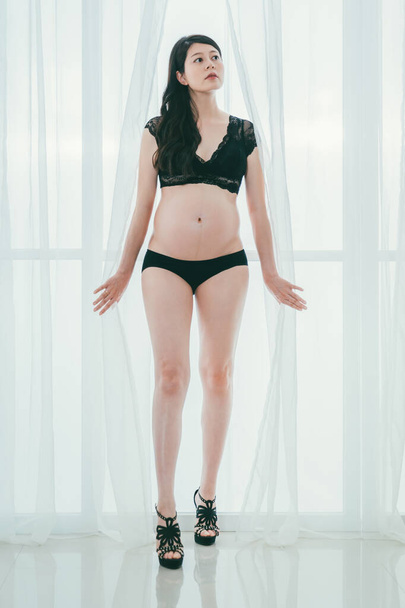 sexy pregnant woman in high heels between curtain - Foto, Bild