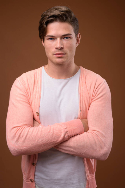 Studio shot of young handsome man against brown background - Foto, immagini