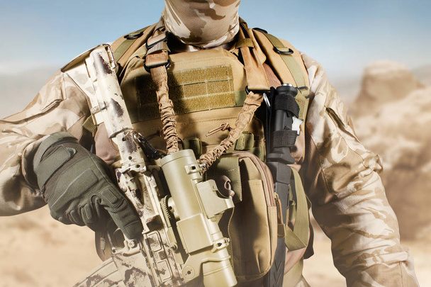 Soldato in uniforme in piedi con fucile nel deserto
. - Foto, immagini