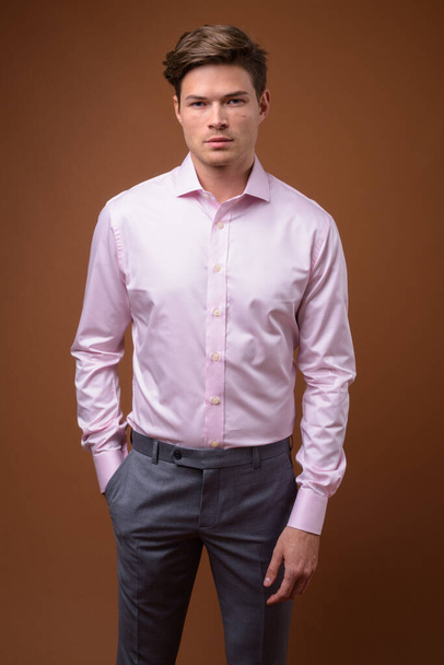 Στούντιο πλάνο του νεαρού όμορφου επιχειρηματία με ροζ πουκάμισο - Φωτογραφία, εικόνα