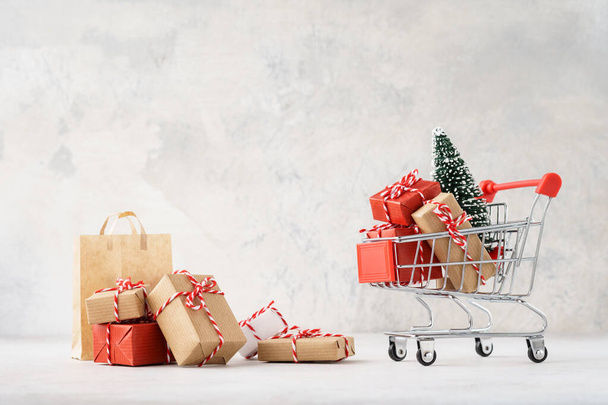 Shopping cart or trolley full of gift boxes and Christmas tree. - Foto, immagini