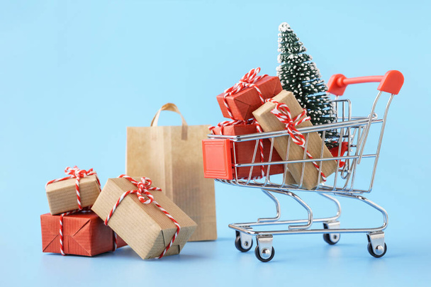 Shopping cart full of various gift boxes and a Christmas tree. - Фото, изображение