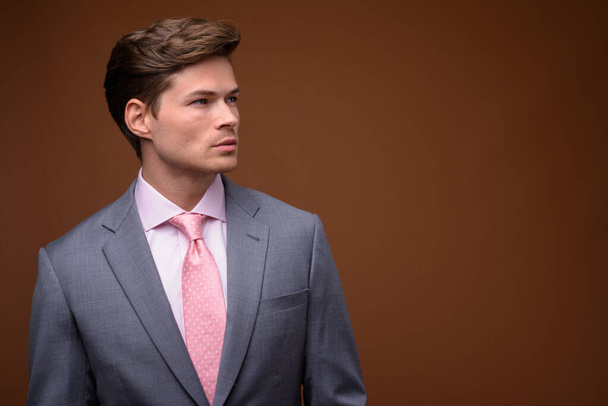 Студийный снимок молодого привлекательного бизнесмена в костюме - Фото, изображение