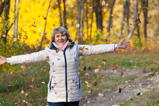 Жінка в куртці гуляє в осінньому парку серед дерев
 - Фото, зображення
