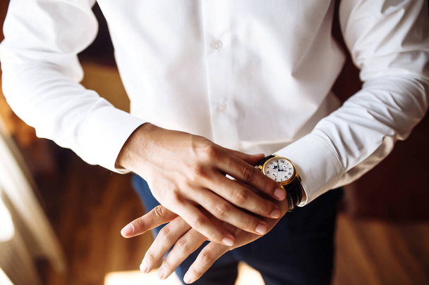 Men's wrist watch, the man is watching the time. Businessman clock, businessman checking time on his wristwatch. Groom's hands in a suit adjusting wristwatch, wedding preparations, groom accessories. - Fotó, kép