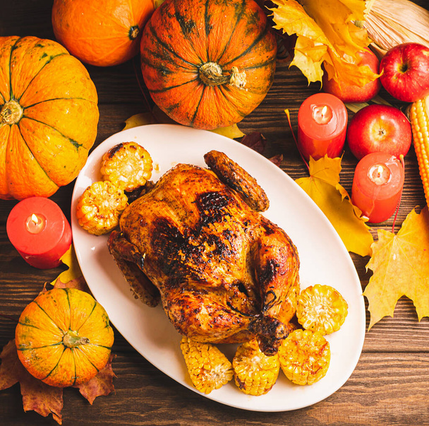Festive turkey or chicken baked by Thanksgiving on white plate and a harvest of seasonal vegetables: pumpkin corn apples - Фото, зображення
