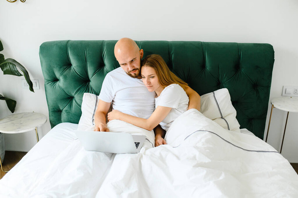 young couple using laptop together in bed  - Φωτογραφία, εικόνα